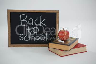 Back to school text with apple and books on white background