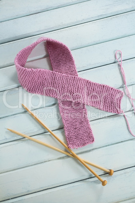 High angle view of pink woolen Breast Cancer Awareness ribbon by crochet needles
