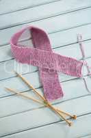 High angle view of pink woolen Breast Cancer Awareness ribbon by crochet needles