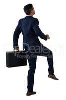 Rear view of businessman with briefcase climbing invisible steps