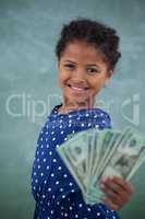 Portrait of girl showing paper currency against wall