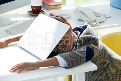 Businessman taking nap on laptop at desk