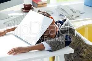 Businessman taking nap on laptop at desk