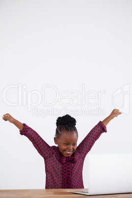 Cheerful businesswoman with arms raised looking at laptop