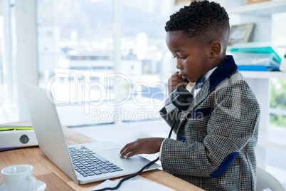 Businessman scrolling on laptop while using telephone