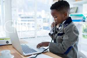 Businessman scrolling on laptop while using telephone