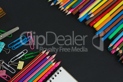 Various multicolored school supplies arranged on black background