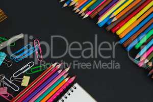 Various multicolored school supplies arranged on black background