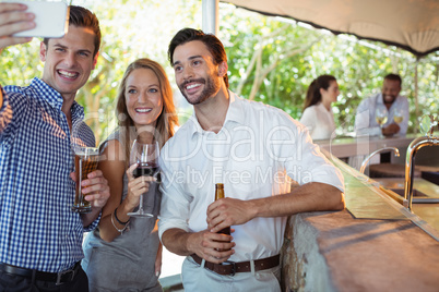 Friends taking selfie while having alcohol at counter