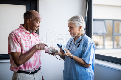Senior man talking to doctor while pointing at blood pressure
