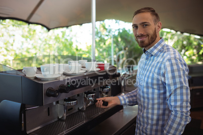 Waiter using tamper to press ground coffee into a portafilter