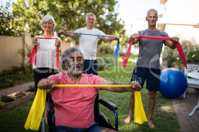 Physically impaired senior man holding ribbon with friends