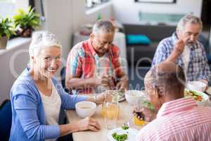 Portrait of senior woman sitting with friends while having breakfast