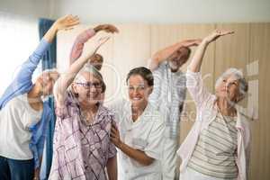 Portrait of smiling female doctor assisting senior woman exercising