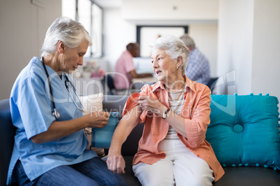 Female doctor checking blood pressure of senior woman