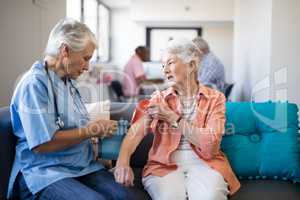 Female doctor checking blood pressure of senior woman