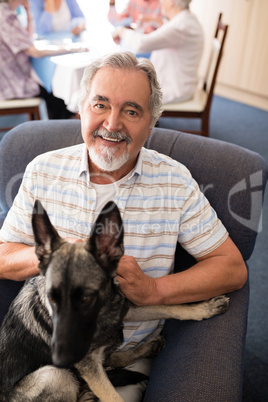 Portrait of smiling senior man sitting with puppy on armchair