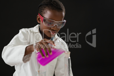 Schoolgirl doing a chemical experiment against black background