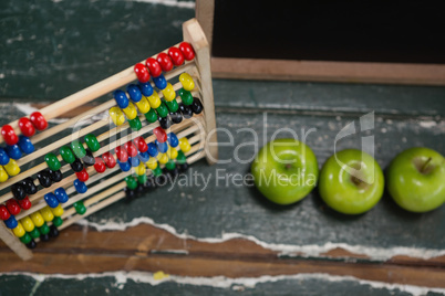 Abacus and green apples on wooden table