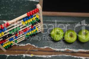 Abacus and green apples on wooden table