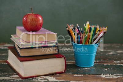 Apple on stack of books with pen holder