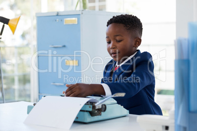 Boy imitating as businessman using typewriter