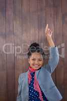 Portrait of smiling girl pretending as businesswoman standing with arms raised