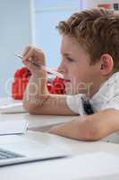 Serious businessman with pen working on laptop