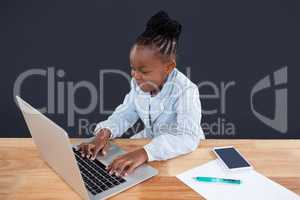 Smiling businesswoman typing on laptop in office