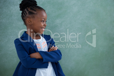 Confident businesswoman with arms crossed against blackboard