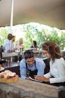 Male waiter and female waitress with digital tablet