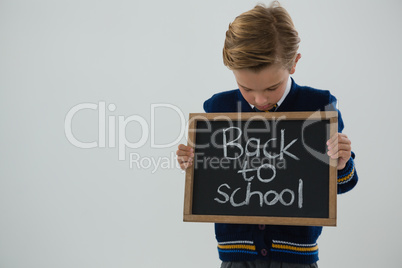 Schoolboy holding slate with text against white background Schoolboy holding slate with text against white background