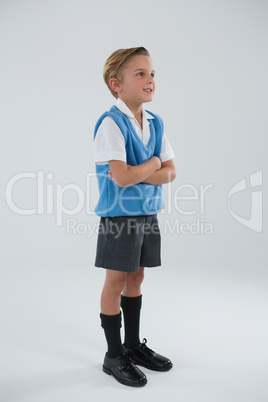 Schoolboy standing with arms crossed against white background Schoolboy standing with arms crossed against white background
