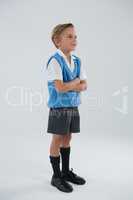 Schoolboy standing with arms crossed against white background