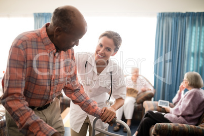 Portrait of smiling female doctor with senior man standing by walker against window