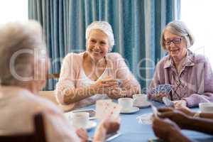 Smiling senior female friends playing cards