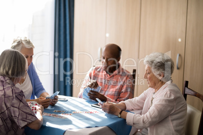 Senior people playing cards at table