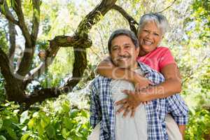 Happy senior man giving piggy bag to woman on a sunny day