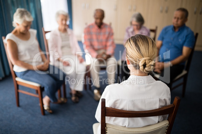 Rear view of female doctor meditating with senior people