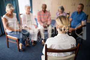 Rear view of female doctor meditating with senior people