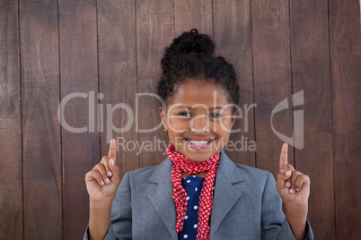 Portrait of smiling girl pretending as businesswoman pointing upwards