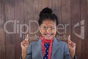 Portrait of smiling girl pretending as businesswoman pointing upwards