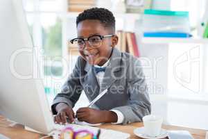 Smiling businessman writing report while looking at laptop
