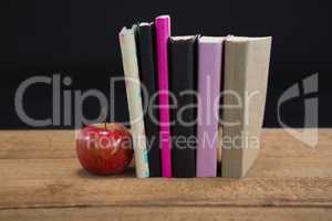 Apple and books on wooden table