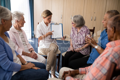 Female doctor pointing while explaining clipboard to seniors