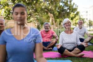 Smiling senior people meditating with trainer