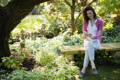 Woman sitting on bench and using mobile phone