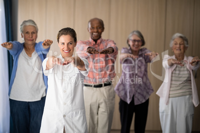 Portrait of smiling female doctor and seniors exercising