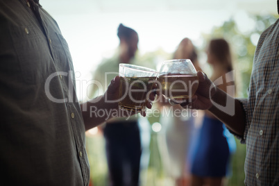 Male friends toasting cocktail glasses in restaurant