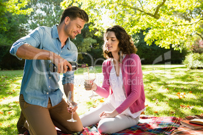 Man pouring wine into womans glass in park
